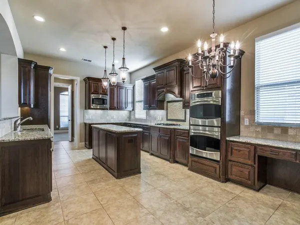 a large kitchen with granite countertop a stove top oven a sink a counter space and cabinets