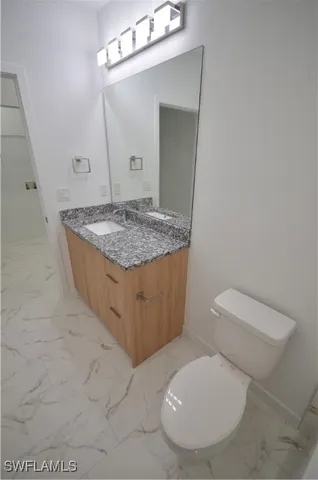 a bathroom with a granite countertop toilet sink and mirror