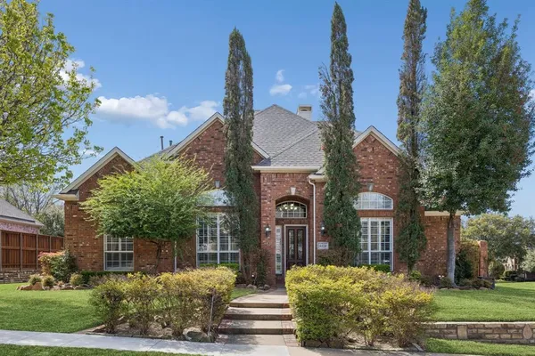 a view of a house with brick walls and a large tree