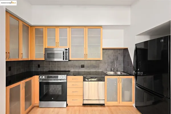 a kitchen with stainless steel appliances granite countertop a stove a refrigerator a sink a dining table and chairs with wooden floor