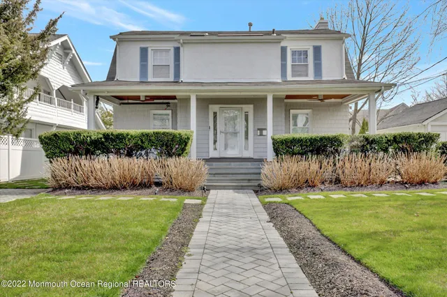 a front view of a house with a yard and potted plants