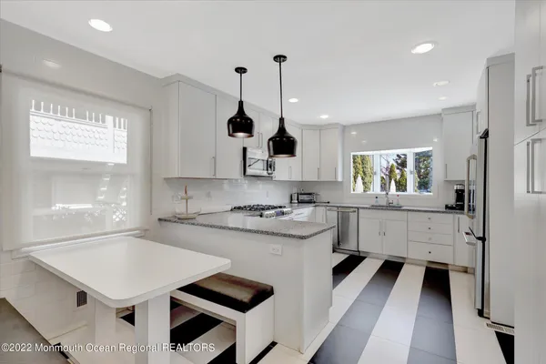 a kitchen with white cabinets appliances and window