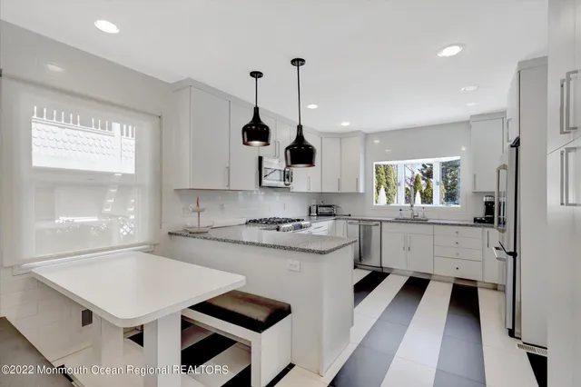 a kitchen with white cabinets appliances and window