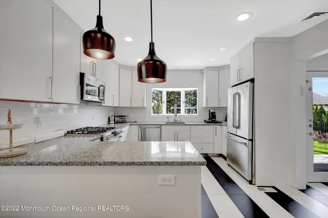 a kitchen with stainless steel appliances granite countertop a sink a refrigerator and a stove