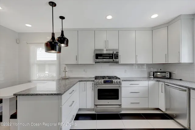 a kitchen with stainless steel appliances a white stove top oven and cabinets