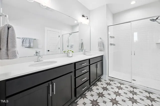 a bathroom with a double vanity sink mirror and shower