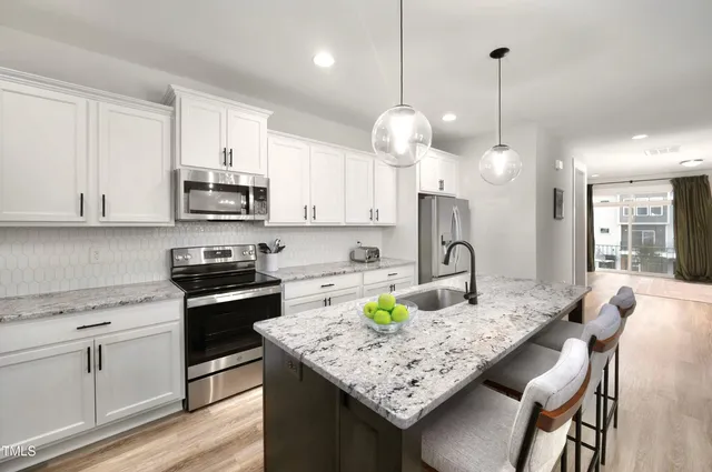 a kitchen with kitchen island granite countertop a sink a stove a microwave a center island and cabinets