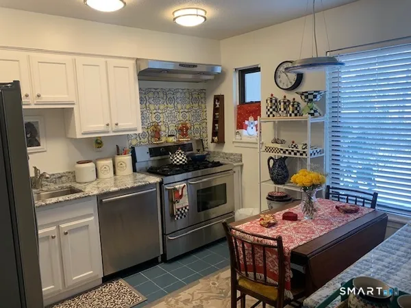 a kitchen with stainless steel appliances a stove a sink cabinets and wooden floor