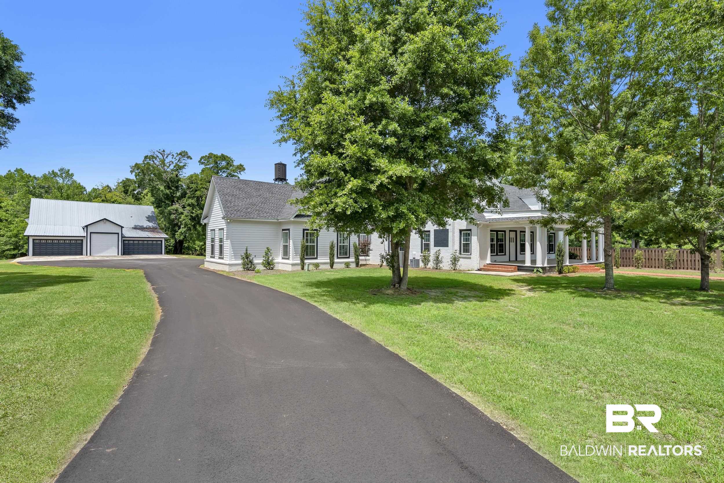43199 Pine Grove Road Bay Minette, AL 36507 - Photo 10 of 71 Asphalt driveway leading to a white residence with a columned porch and a separate multi-bay garage structure with a metal roof