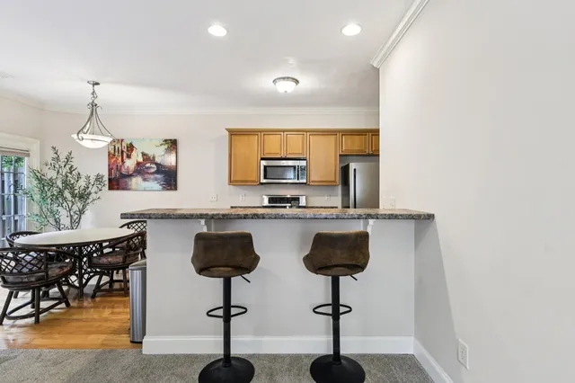 a kitchen with stainless steel appliances granite countertop a sink a stove a dining table and chairs