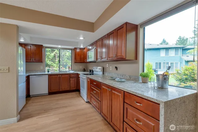 a kitchen with stainless steel appliances granite countertop wooden cabinets a stove a sink and a large window