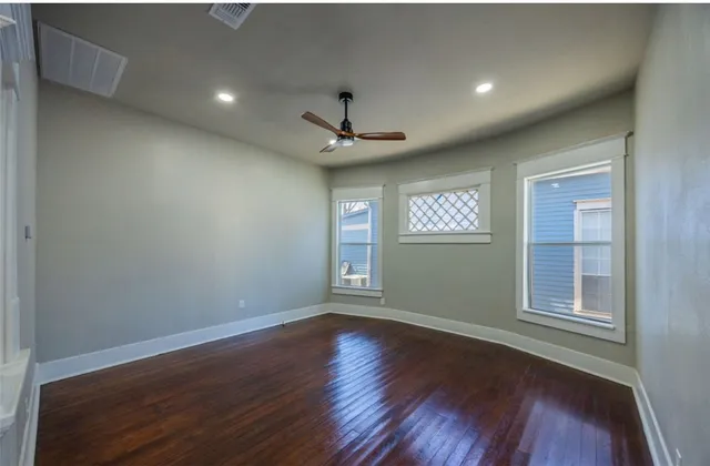 an empty room with wooden floor chandelier and windows