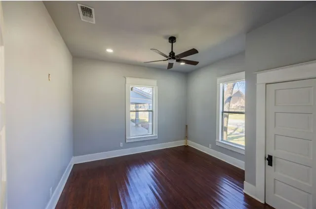 a view of an empty room with a window and wooden floor