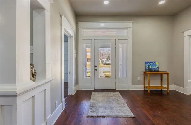 a kitchen with stainless steel appliances sink stove refrigerator and white cabinets with wooden floor