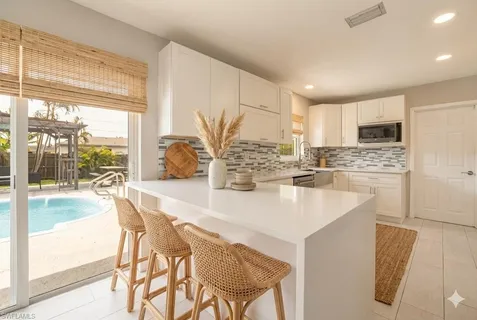 a kitchen with kitchen island granite countertop a stove a sink a oven with a dining table and chairs