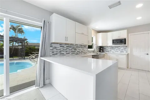 a kitchen with kitchen island granite countertop a sink stove and cabinets