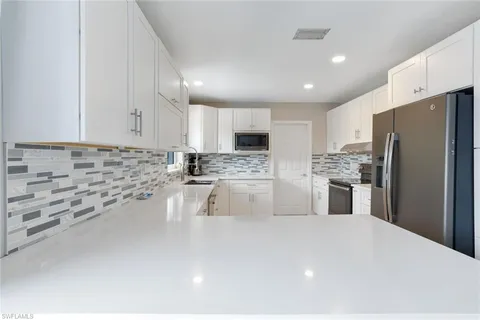 a kitchen with stainless steel appliances a refrigerator sink stove and white cabinets