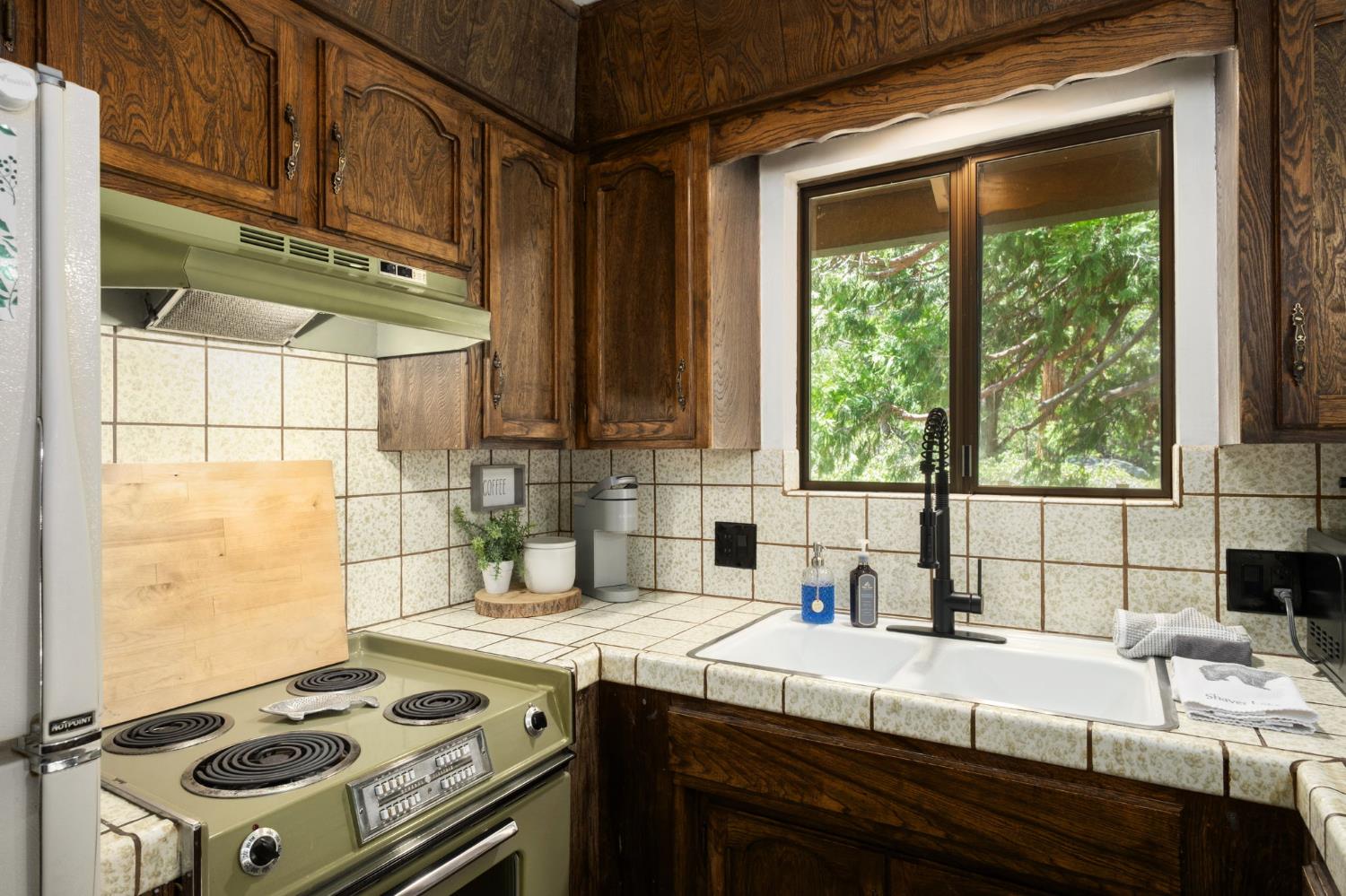 42488 Rock Ledge Road Shaver Lake, CA 93664 - Photo 17 of 26 a kitchen with a stove a sink a refrigerator and window
