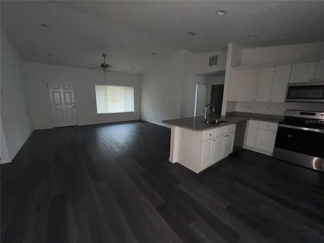 a kitchen with stainless steel appliances a kitchen island hardwood floor sink stove and granite counter top