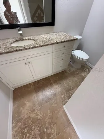 a bathroom with a granite countertop sink and a toilet