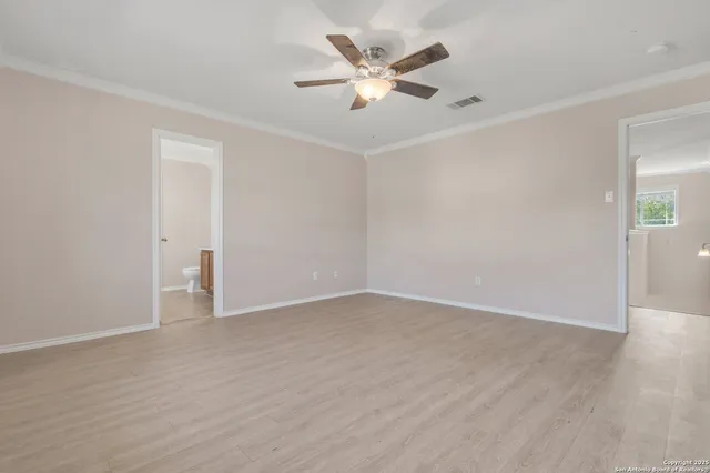 an empty room with wooden floor and ceiling fan