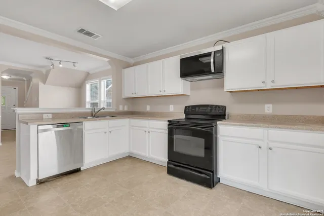 a kitchen with granite countertop white cabinets sink and stainless steel appliances