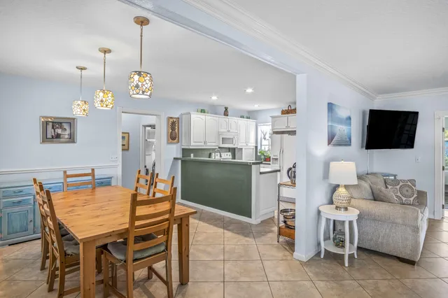 a view of a dining room and livingroom with furniture wooden floor a rug a flat screen tv and a chandelier