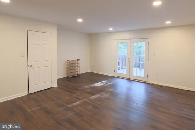 an empty room with wooden floor and natural light