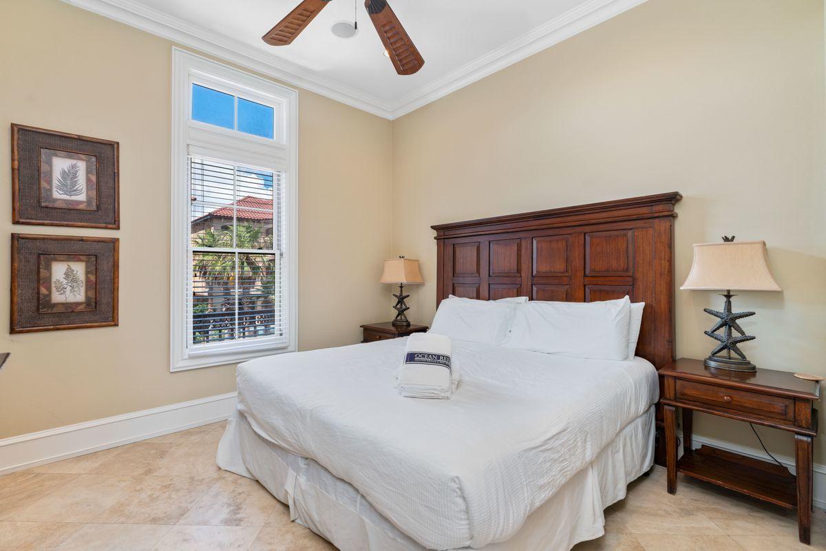 4789 Ocean Boulevard Destin, FL 32541 - Photo 26 of 47 a bedroom with a large bed and a chandelier