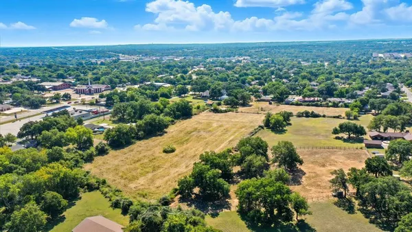 an aerial view of residential houses with outdoor space and trees