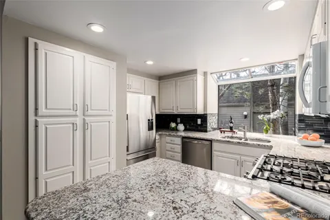 a kitchen with stainless steel appliances granite countertop a refrigerator and a stove top oven