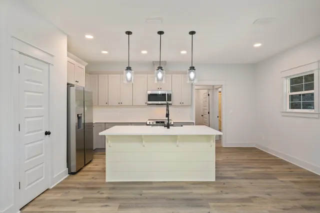 a view of a kitchen with kitchen island a sink wooden floor and a window