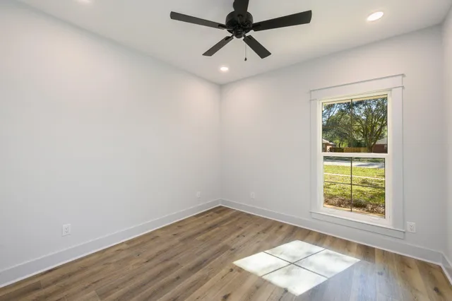 an empty room with wooden floor and windows