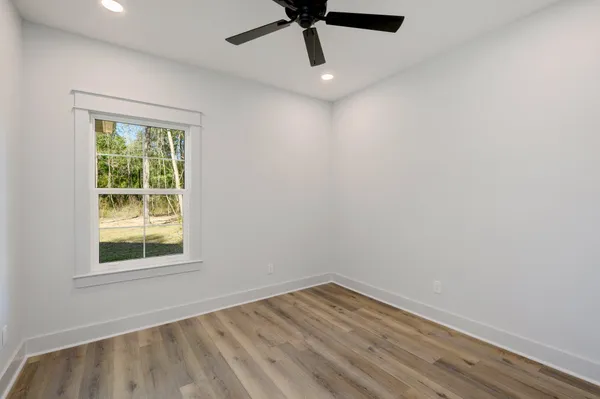 an empty room with a window and a ceiling fan