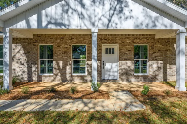 a front view of a house with a large tree in front