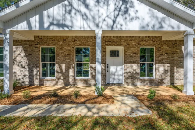 a front view of a house with a large tree in front
