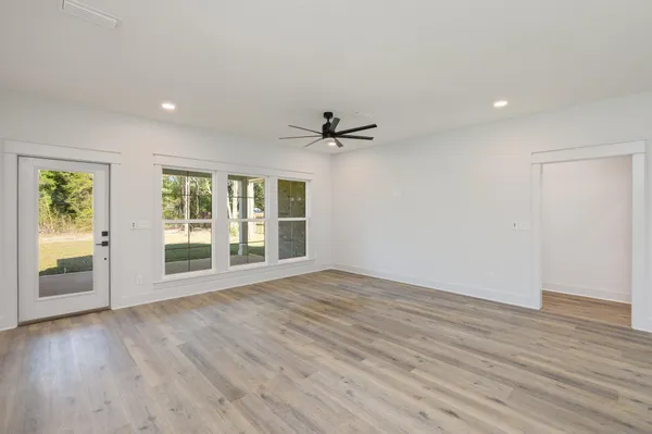 a view of an empty room with a window and wooden floor