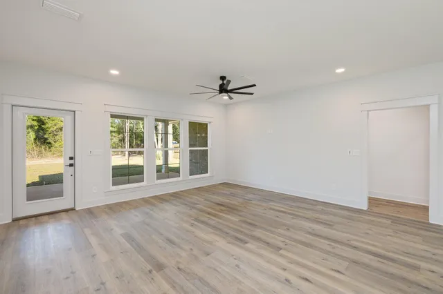 a view of an empty room with a window and wooden floor