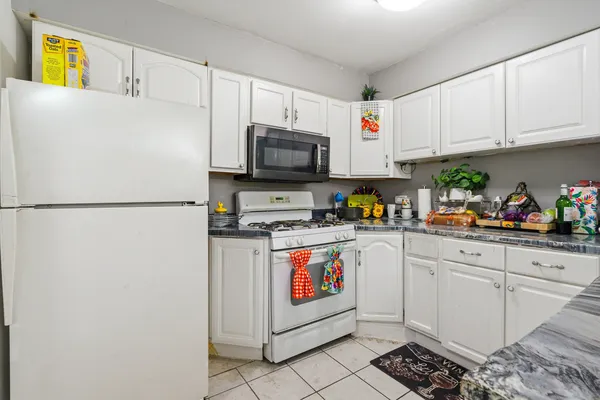a kitchen with stainless steel appliances granite countertop a refrigerator sink and white cabinets