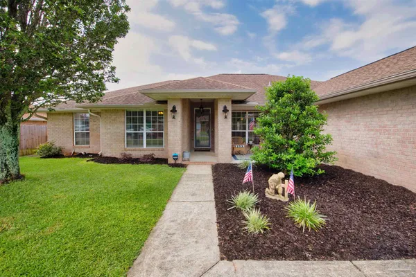 a front view of a house with a yard and potted plants