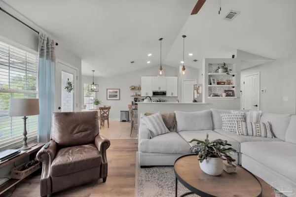 a kitchen with stainless steel appliances granite countertop a stove top oven a sink a dining table and chairs with white cabinets