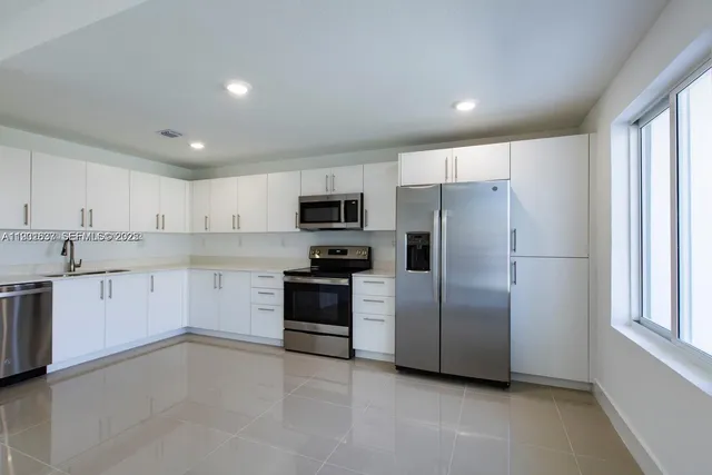 a kitchen with granite countertop white cabinets and stainless steel appliances