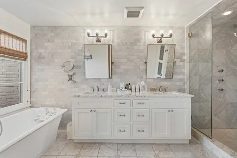 a bathroom with a double vanity sink large mirror and a bathtub