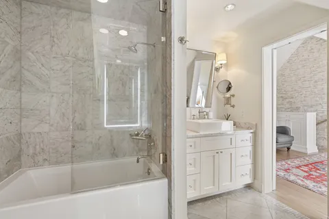 a bathroom with a bathtub shower sink and mirror