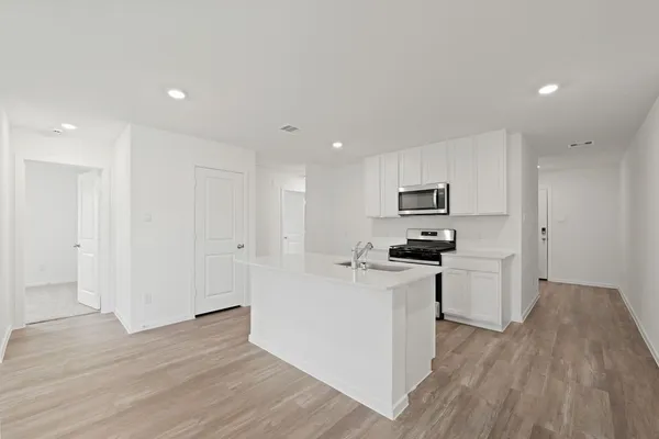 a kitchen with stainless steel appliances granite countertop a stove top oven a sink and a refrigerator