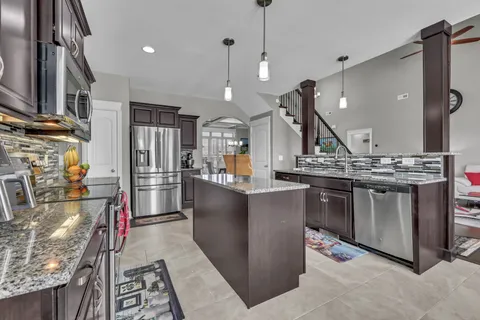 a kitchen with stainless steel appliances kitchen island granite countertop a stove and a refrigerator