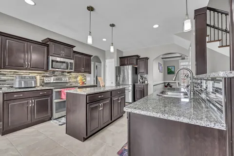 a kitchen with stainless steel appliances granite countertop a sink refrigerator and cabinets