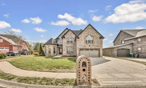 a view of a white house next to a yard with big trees