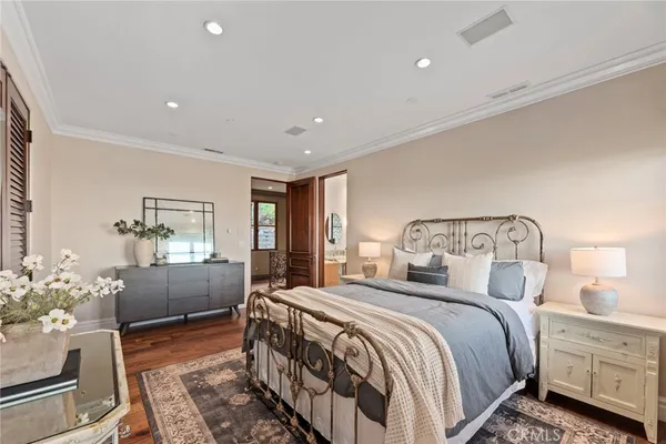 a bedroom with a large bed and potted plant on the dresser