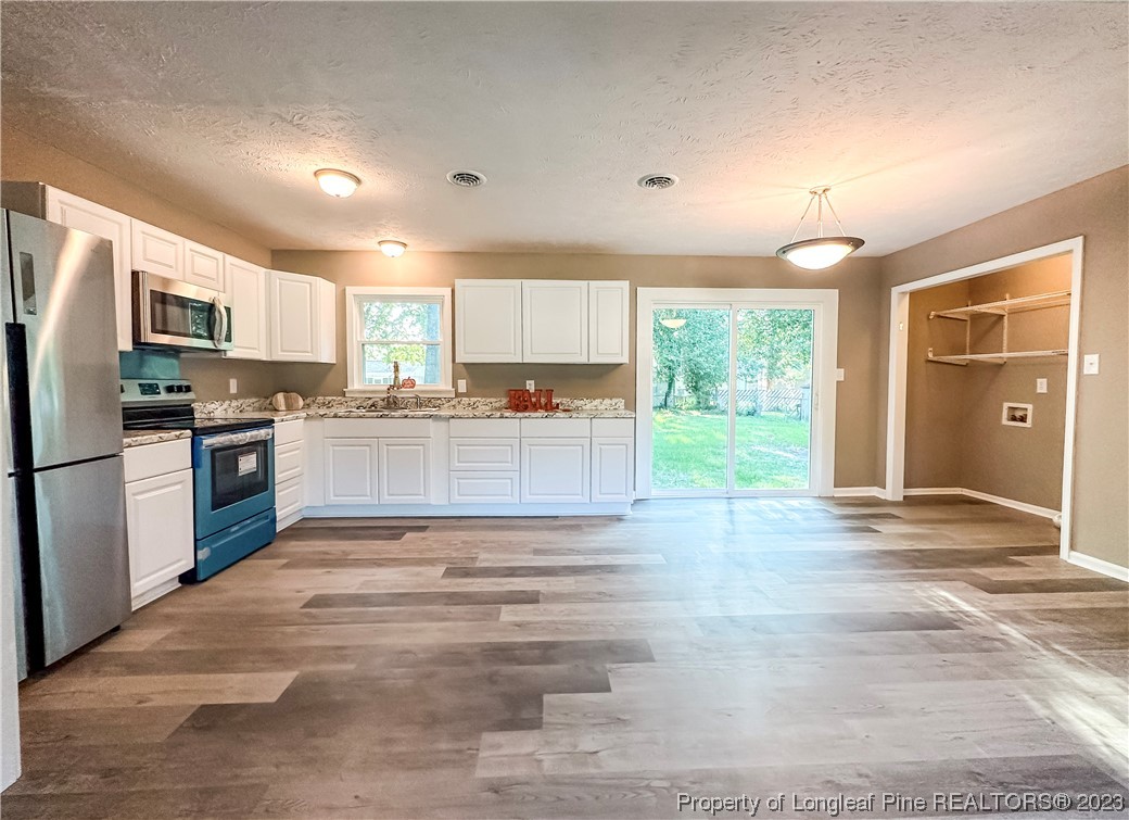 1645 Flintshire Road Fayetteville, NC 28304 - Photo 6 of 22 a large kitchen with kitchen island a stove a sink dishwasher and a refrigerator with wooden floor